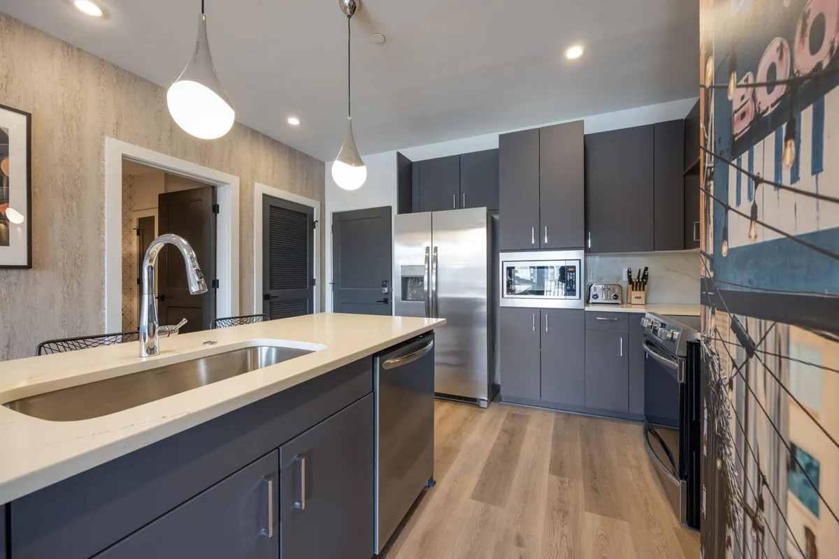 A bright, contemporary kitchen featuring a spacious island, stainless steel appliances, and eye-catching decorative wall art. The layout highlights ample counter space and modern functionality, making it ideal for cooking, entertaining, and family gatherings.
