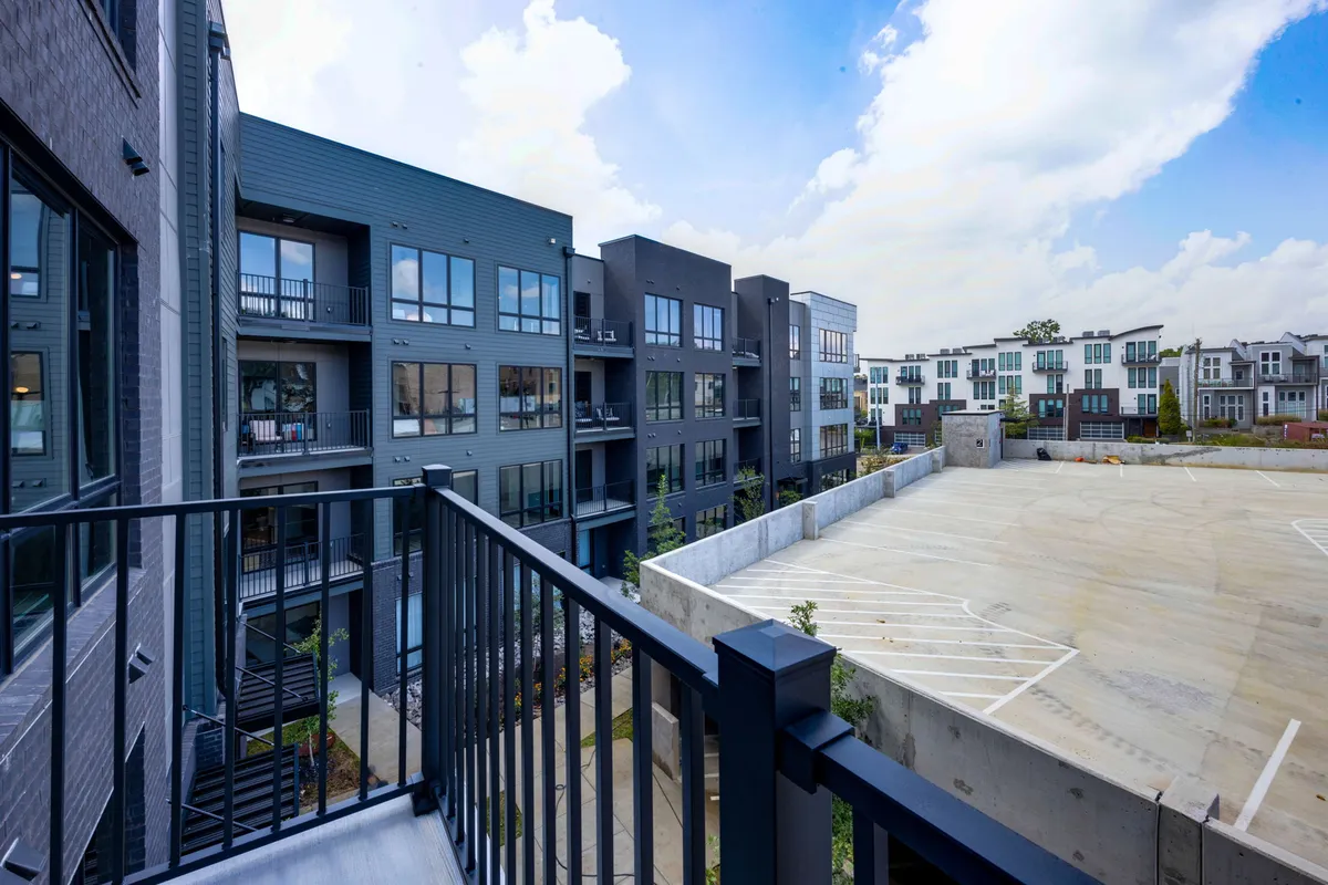 A modern apartment complex with balcony railings, an open courtyard, and inviting communal spaces. The setting suggests opportunities for relaxation and social gatherings, representing the home base for visitors attending campus events or exploring the city.